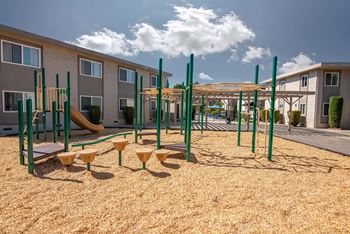 a playground with a jungle gym and slides in front of a building